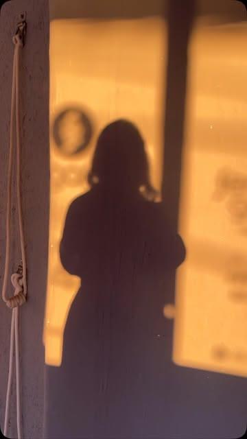 Sombra de uma pessoa projetada na parede pela luz dourada do fim de tarde
